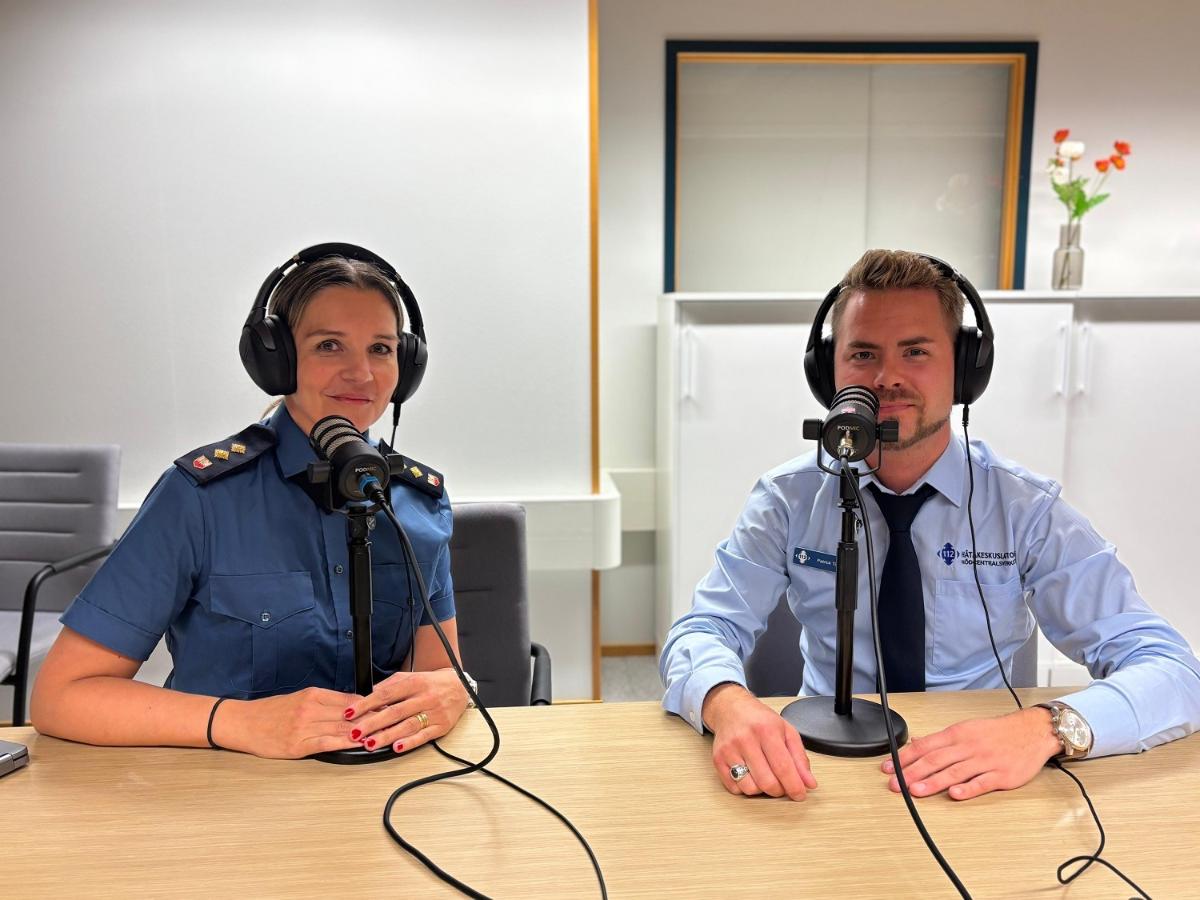 Titta Lindholm ja Patrick Tiainen istuvat pöydän ääressä mikrofonit edessään ja kuulokkeet päässään.