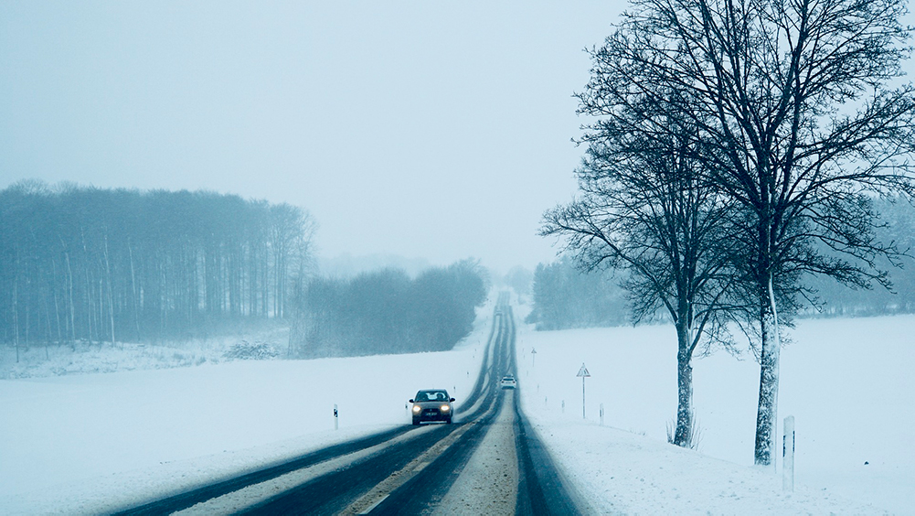 Harmaa talvinen kuva liikenteestä, jossa loskaa tiellä ja muutama auto kulkemassa omiin suuntiinsa.