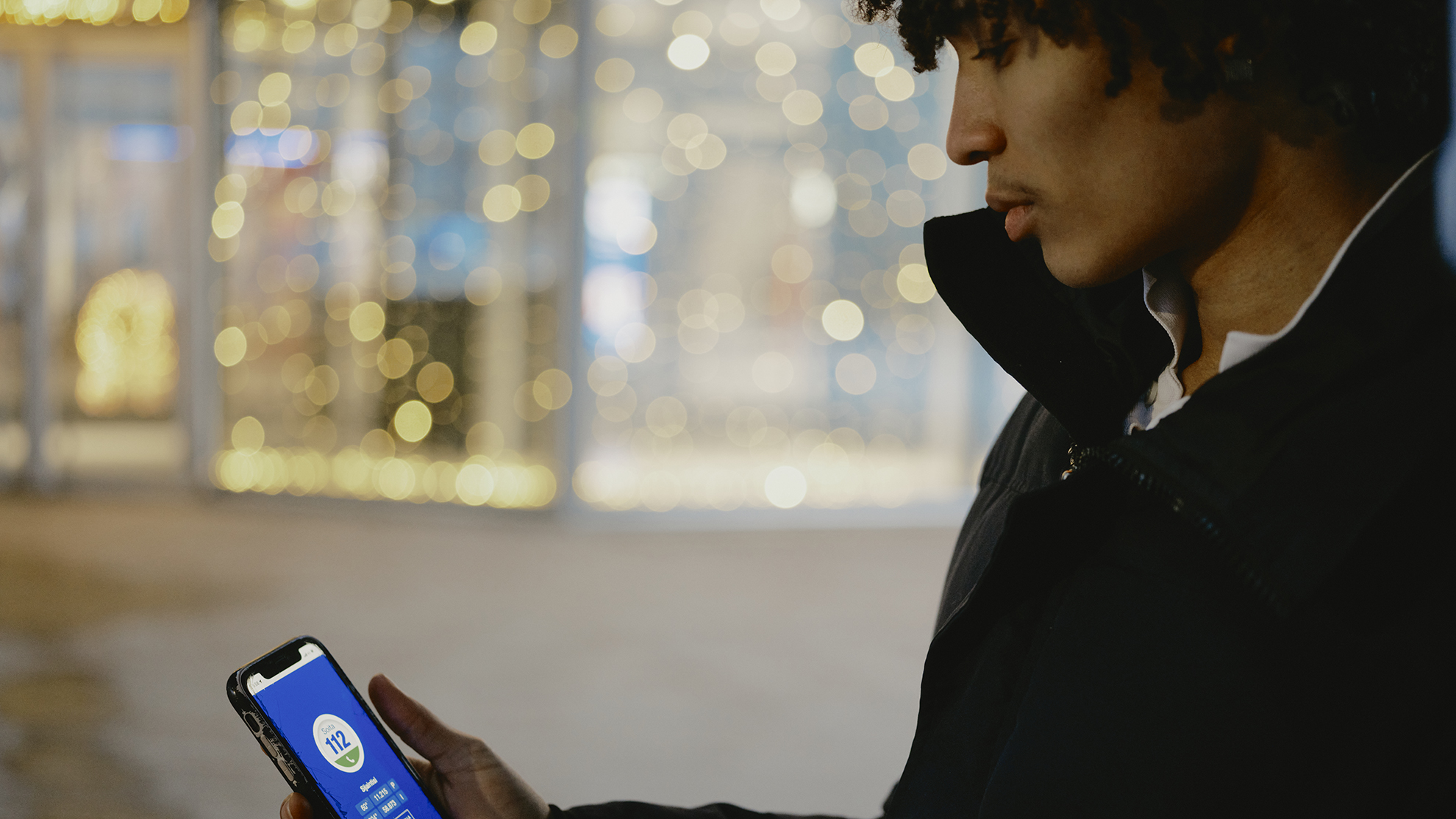 Nuorella miehellä on kädessään puhelin. Puhelimen näytöllä on 112 Suomi -sovellus.